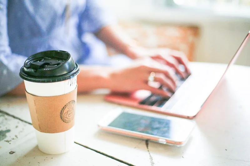 A freelancer working from a laptop with coffee and phone nearby