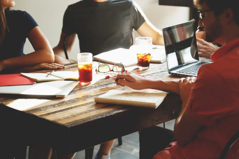 A small team gathered around a table with laptops and notebooks