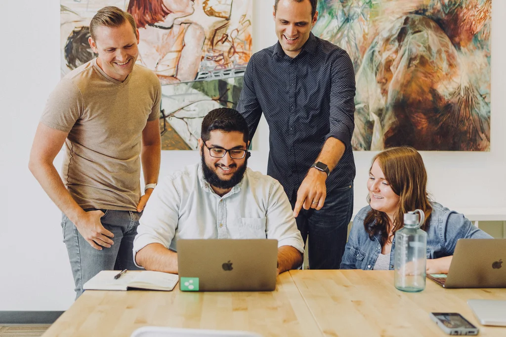 A small team gathered around a laptop — the everyday collaboration IDConnect keeps identity consistent across